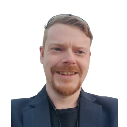 Joe Loe smiling, with red hair and a beard, in a navy jacket.