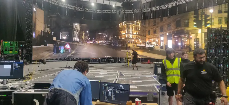 A night-time city street on the LED volume, with crew and playback kit on the studio floor.